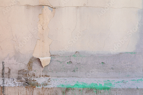 weathered concrete wall with heavily peeling paint and cracks