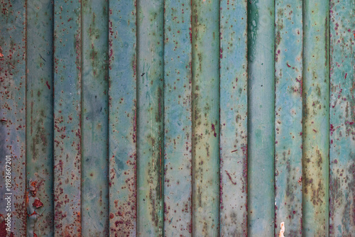 weathered teal metal wall with heavy rust and vertical lines