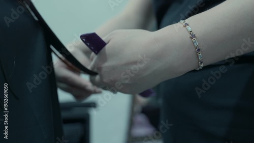 A hairdresser cuts the ends of his client's hair in a beauty salon.