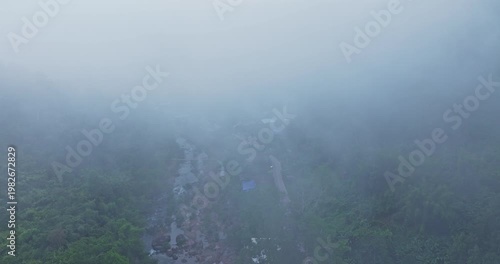 A breathtaking aerial view of Sapan Village in Nan, Thailand, covered by a magical sea of mist at sunrise. Warm morning light illuminates the mountain valley while fog drifts through lush green hills