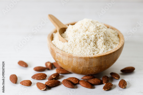Almond meal, Almond flour, in wooden bowl with almond nuts on white table.