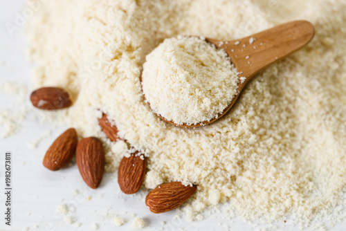 Almond meal, Almond flour, in wooden bowl with almond nuts on white table.