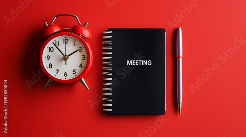Essential meeting preparation flat lay, a vibrant red alarm clock, black spiral-bound notebook labeled 