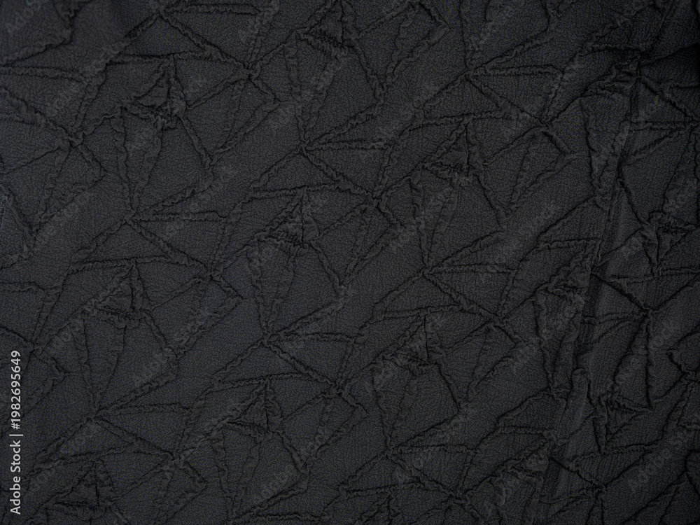 Fototapeta premium Dark charcoal fabric texture with geometric stitched quilt pattern, wrinkled textile surface, abstract background with subtle shadows and seams.