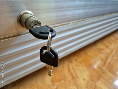 Close-up of key inserted in metal cabinet lock on wooden floor with shallow depth of field