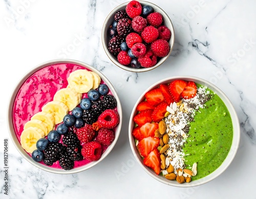 A vibrant and healthy arrangement of smoothie bowls with fresh fruits and toppings on a marble surface