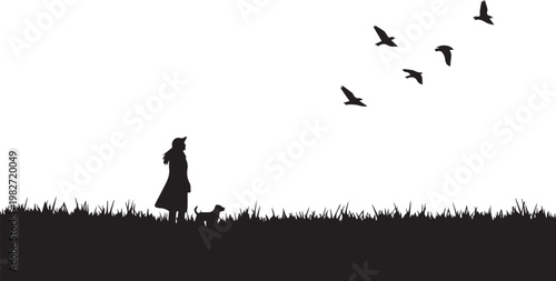 Silhouette of a woman and dog with flying birds at dusk