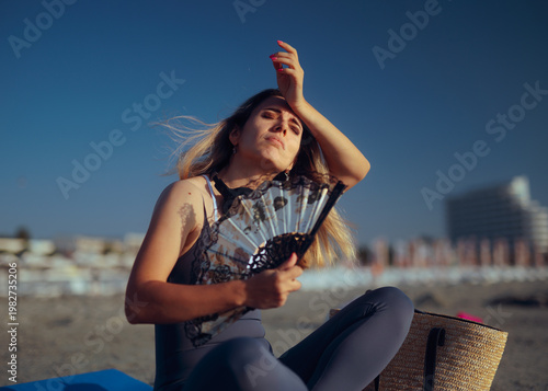 Photos Woman Using a Hand Fan Feeling too Hot at the Beach