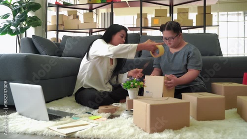 Woman entrepreneur and assistant packing cardboard boxes on living room floor with laptop and supplies, representing small business, e-commerce and home-based logistics
