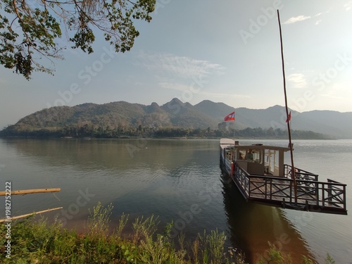 Traditional River Boat with Lao Flag and Mountain Landscape