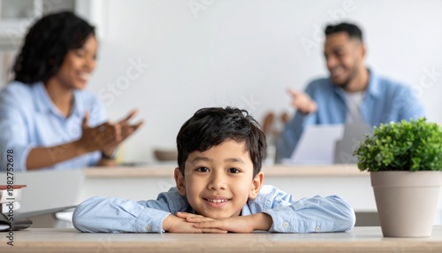 Happy young boy smiling at camera with parents in background.