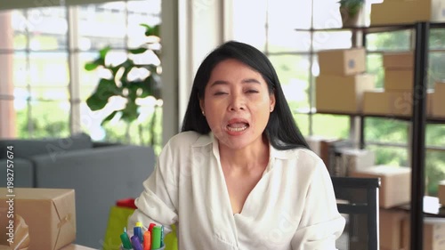 Woman business owner speaking to camera at desk with packaging boxes and office supplies, representing online selling, content creation and e-commerce business
