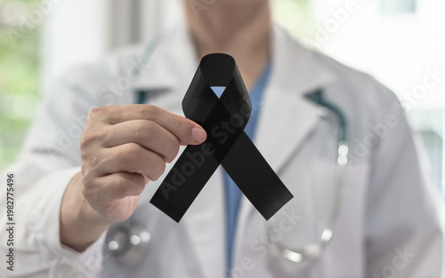 Black ribbon awareness in doctor's hand for Melanoma and skin cancer, Narcolepsy, Primary Biliary Cirrhosis (Cholangitis), Sleep Apnea Disorders and for mourning