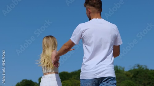 Happy young couple holding hands while running, having fun. Man and woman spending time together in the city. Bonding, love and relationship concept. Real time