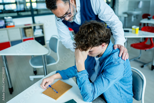 Cuadro en lienzo Teacher supporting struggling student with learning difficulties during lesson