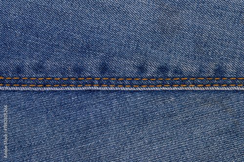 Foto Blue denim fabric with visible seam and orange stitching detail
