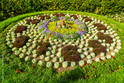 Cuadro en lienzo A clock in the garden with a colorfully planted flower bed.