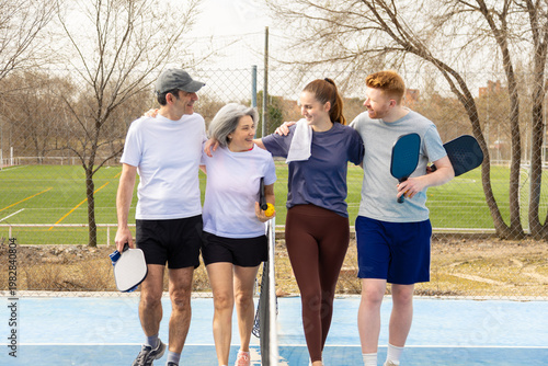 Multi generational pickleball players walking together on court