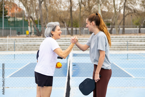 Women pickleball players shaking hands on court