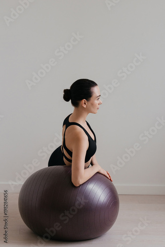 Woman doing Pilates on fitness ball for balance exercise and healthy lifestyle
