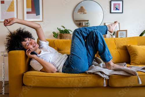 Happy woman relaxing on sofa using smartphone