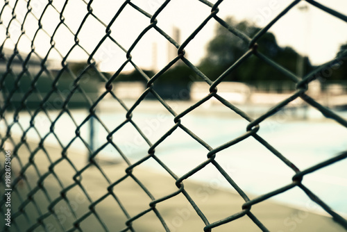 Steel wire mesh fence at an outdoor sports court. Concept of boundary, security, and athletic background.