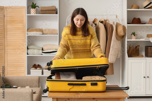 Young woman packing suitcas...