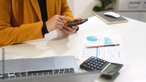 women hand working with samrtphone and laptop computer with documents on office desk.