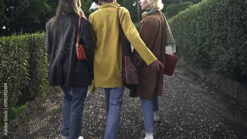 Three women walking on a garden path.