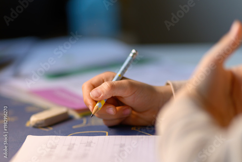 Quadro su tela Close-up of a young boy pupil student's hand holding a pencil and doing homework