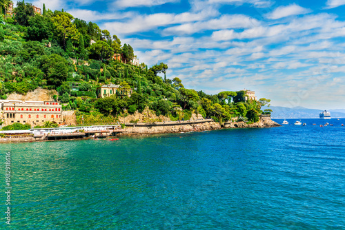 Beautiful italian coastline with green mountains and blue azure sea bay of Portofino gulf in Liguria. Panoramic landscape of luxury italian resort with boats in sea and cloudy sky.