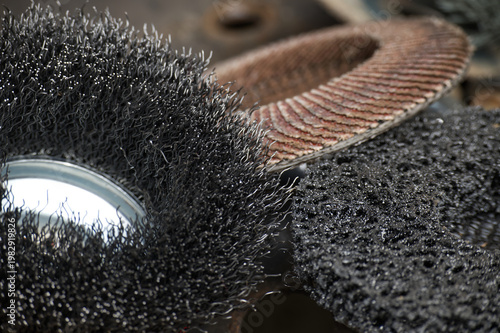 Abrasive tools including wire wheel, flap disc, grinding wheel on workshop surface showing texture
