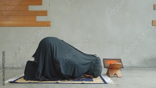 Muslim woman performing prayer alone with Quran placed on a wooden stand, representing devotion, solitude, and spiritual connection.
