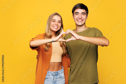Young couple two friends family man woman wear shirt casual clothes together showing shape heart with hands heart-shape sign isolated on pastel plain light yellow background studio. Lifestyle concept.