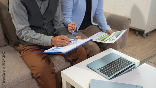 Business team analyzing documents, graphs, and data with a laptop, tablet, and smartphone. Collaboration, strategy, and success in a modern office.