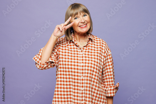 Elderly satisfied cool gray-haired woman 50s years old wear beige t-shirt shirt casual clothes showing cover eye with victory sign isolated on plain pastel light purple background. Lifestyle concept.