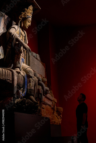 Foto A devout man pays homage to a giant Buddha in a Buddhist grotto