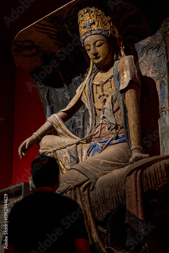 A devout man pays homage to a giant Buddha in a Buddhist grotto