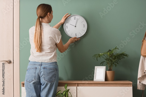 Young woman hanging clock o...