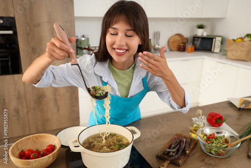 Young woman making soup in ...