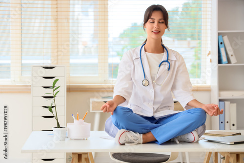 Female doctor meditating on table in clinic