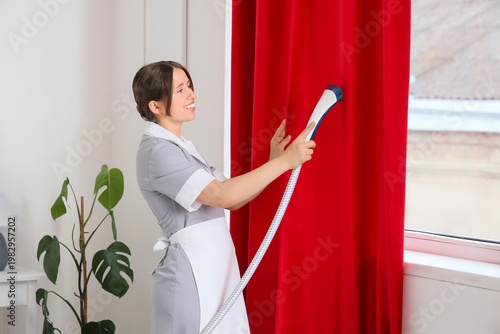 Young chambermaid steaming ...
