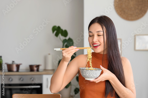 Young Asian woman eating ta...