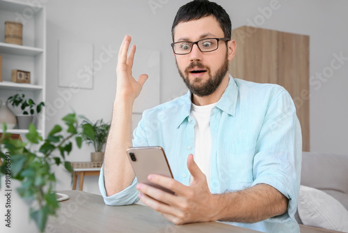 Surprised young man using m...