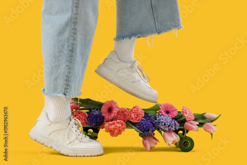 Konstfotografi Legs of young woman in stylish sneakers and skateboard with beautiful flowers on