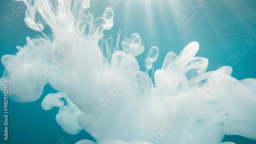 White ink cloud swirling in clear blue water with cinematic sunlight rays from above