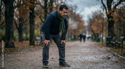 Middle-aged man struggling to breathe while walking in park during autumn - Concept of World Asthma Day  
