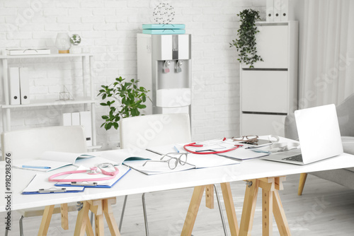 Medical intern's eyeglasses with copybooks and laptop on table in clinic