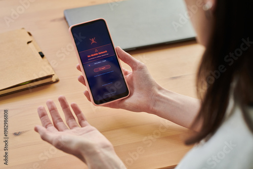 Fényképezés Young adult woman holding smartphone showing no mobile network error while working at desk, expressing frustration