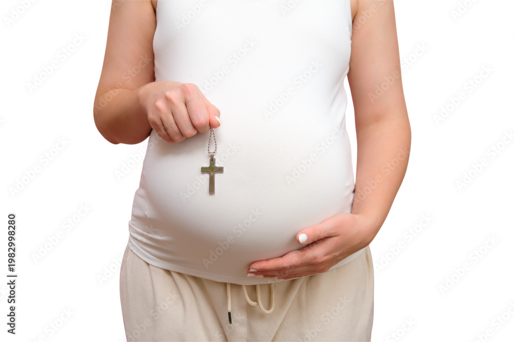 Wall Mural Pregnant woman holding a religious catholic cross in her hand, studio pink backg